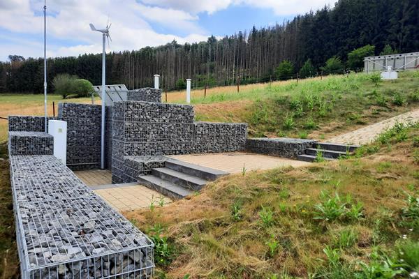 Ansicht auf den Einstieg mit Schaltschräken und Windrad und Photovoltaik – Der Speicher arbeitet nun Autark von Außenstrom und wird über Funk gesteuert